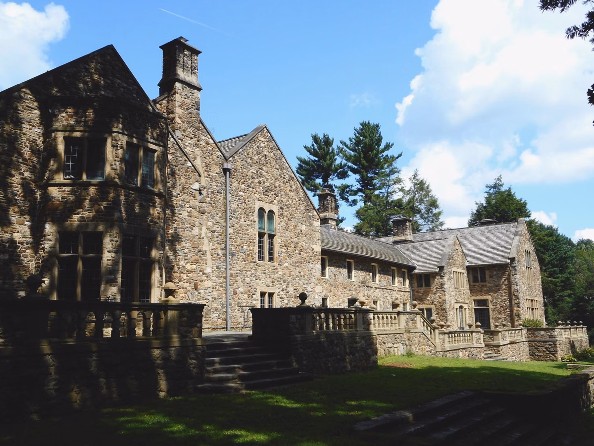 The rear of Hunting Hill Mansion with stone steps, terrace walls and lawn at Ridley Creek State Park