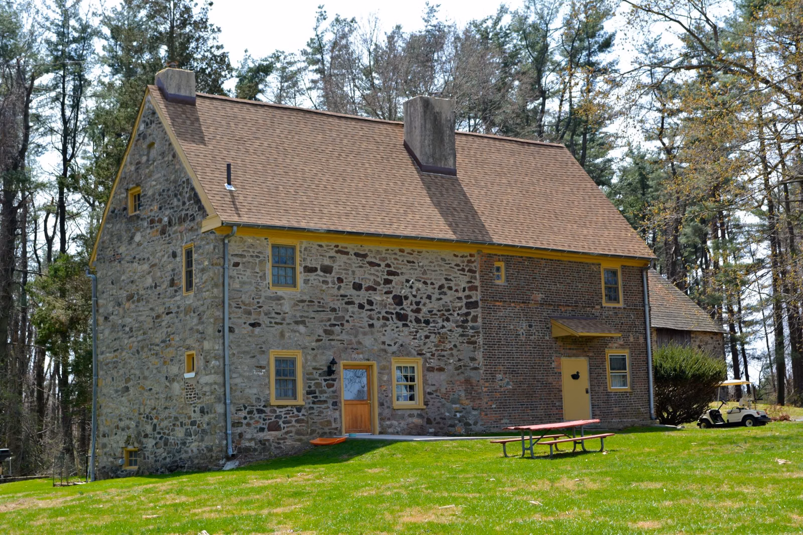 A picnic table on the lawn in front of the historic stone Worrall house in Ridley Creek State Park