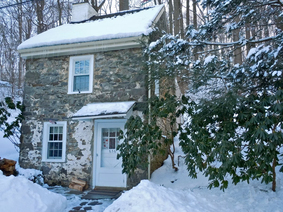 A two-story stone mill workers' house in snow near Sycamore Mills, a private residence in Ridley Creek State Park